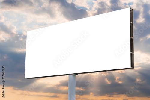 Blank white billboard against the warm sunset sky. Sun beams are shining through dramatic clouds - mock up. Marketing, white screen, mockup, copy space, consumerism and outdoor advertising concept