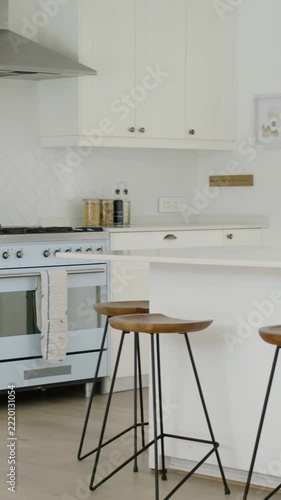 Vertical video: Panning shot starting on stove in kitchen, showing island, stools and oven