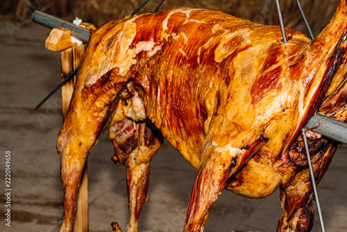Golden brown whole roasted lamb on a spit at a traditional barbecue.