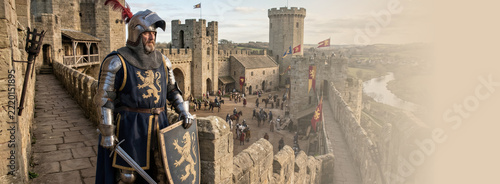 Medieval knight in plate armor standing on castle wall overlooking fortress courtyard. Historical reenactment of kingdom life. Warrior guarding defense rampart of stone citadel. Banner with copy space