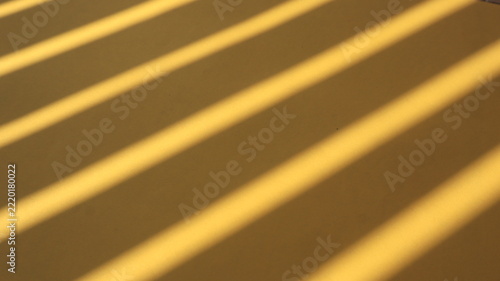 Colorful paper sheets with dramatic linear fence shadows cast by warm natural sunlight