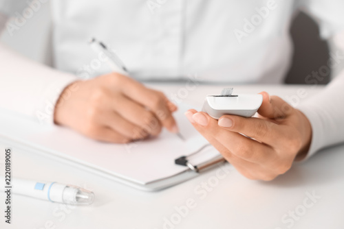 Diabetes management and blood glucose monitoring, doctor or patient recording health data with a glucometer and medical chart in a clinical office