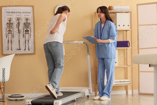 Physical therapy and rehabilitation, patient with back pain walking on treadm...
