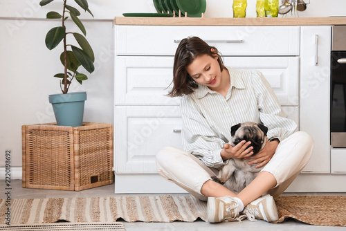 Pet companionship and mental health, young woman sitting on kitchen floor cud...