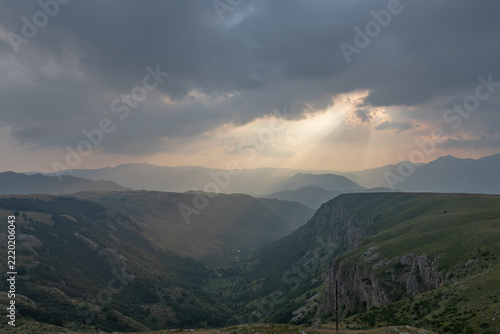 Fotografie Dramatic panoramic landscape of a mountain valley under overcast cloudy skies wi