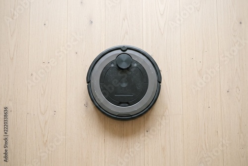 Unbranded robot vacuum seen from above on a wooden floor