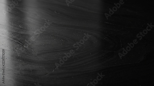 Close up of wet obsidian stone surface with reflective light patterns