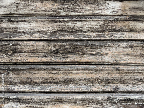 Old weathered wooden planks with heavily textured peeling surface, natural grain and rustic gray brown tones, creating a distressed wood background.