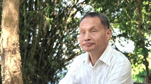 Slow Motion of Thai Senior Man Sitting Outdoors and Looking Around and Up