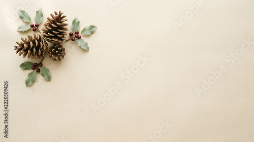 Christmas pinecones and holly berries arrangement isolated on a light beige paper background