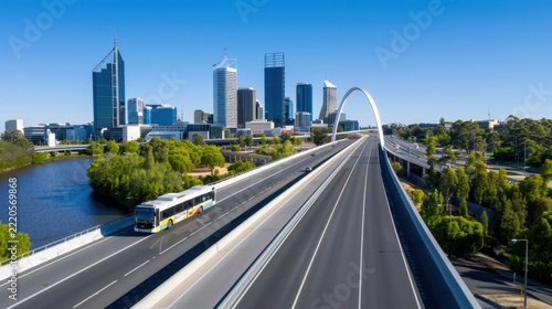 Modern Urban Landscape with Scenic River, Bus Transit, and Skyscrapers Under Clear Blue Sky