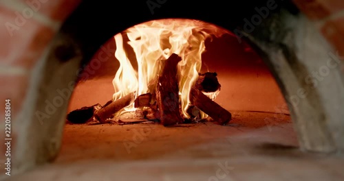Glowing embers igniting, stacked firewood is burning inside masonry oven, sending heat for baking