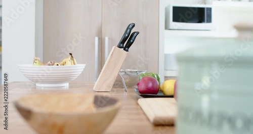 Knife block, camera pulling focus forward, revealing red pepper on cutting board, shifting focus