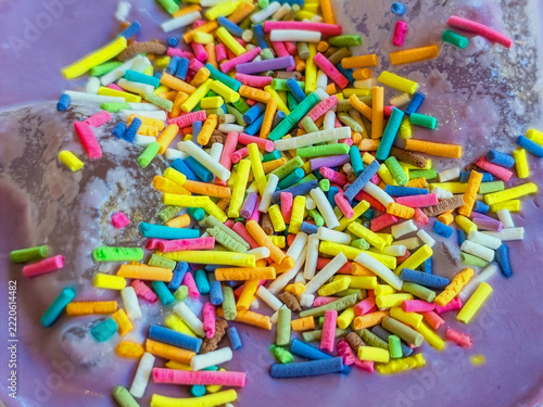 Fotografie Close up of colorful rainbow sprinkles on creamy purple ube latte or lavender raf foam, sweet texture for a dessert and coffee background