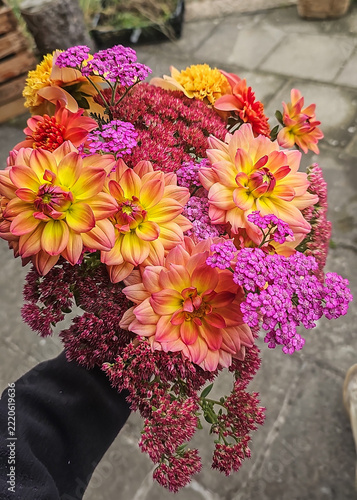 Farbenfroher Herbstblumenstrauß mit orangefarbenen Dahlien, rosa Schafgarbe und Fetthenne