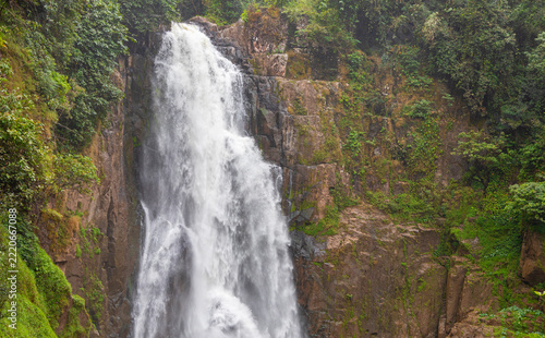 Powerful Haew Narok waterfall in Khao Yai National Park.A majestic view of Haew Narok waterfall cascading down a steep rocky cliff surrounded by lush green tropical jungle in Thailand.