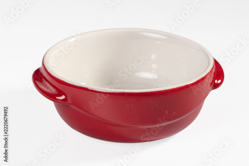 Fotografie Empty red ceramic ramekin with two handles and white glazed interior on white ba