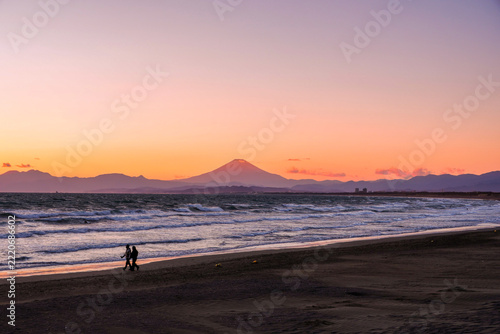 夕焼けの富士山と手をつないで歩く二人｜江の島のロマンチックな旅行・デート素材