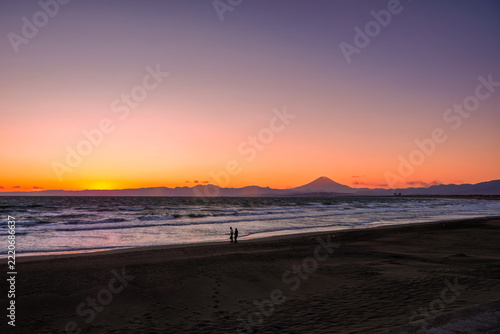 夕焼けの富士山と手をつないで歩く二人｜江の島のロマンチックな旅行・デート素材