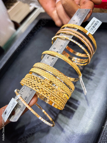 Gold bangles with price tags stacked on a sizing stick in the gold souk of Deira, Dubai, United Arab Emirates