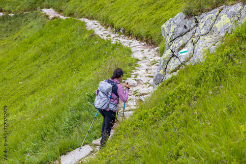 Obraz na plátně Woman Hiking on Rocky Path Next to Trail Marker