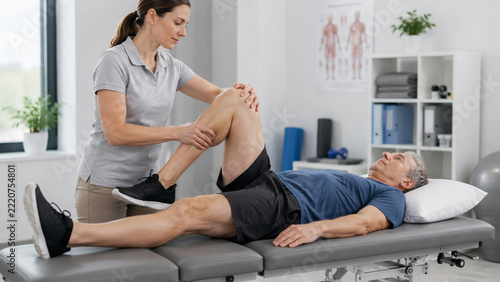physiotherapist assisting patient with knee rehabilitation exercise on treatment table