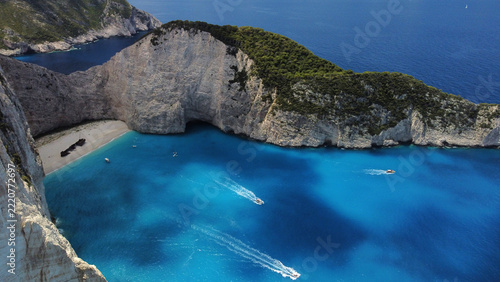 Fotografie Wide aerial view of a turquoise cove with cliffs and a beach shipwreck