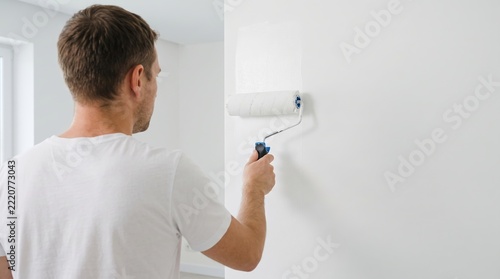 Man Painting Wall with Roller Brush in Bright Room with Natural Light