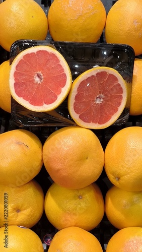 Stacked Pink Grapefruits With Two Fresh Cut Halves Displaying Juicy Red Pulp On Market Shelf