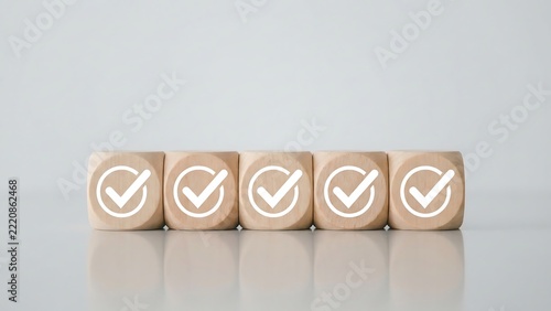 Five wooden cubes arranged in a row on a white surface, each featuring a white circular checkmark icon, representing task completion and success