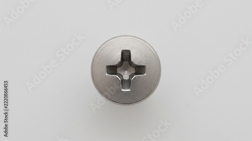 A metallic Phillips cross head screw viewed from above, featuring a clean industrial design and subtle shadows, isolated on a neutral background for hardware, construction, and engineering application