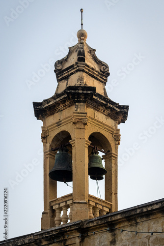 Historic Bell Tower With Two Bronze Bells and Weathered Stone Church Architecture At Dusk