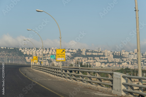 Empty highway curving toward Haifa cityscape on Mount Carmel hillside residential apartment buildings and urban architecture