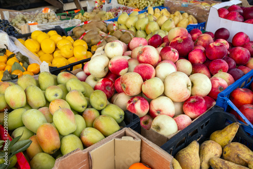 Large assortment of fresh apples, pears, lemons, kiwis and grapes displayed for sale at a fruit market