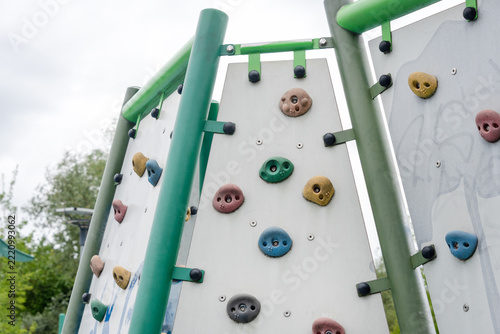 Children climb a colorful rock wall at an outdoor playground. Outdoor play and fitness themes: childhood activity, teamwork, recreation, summer fun.