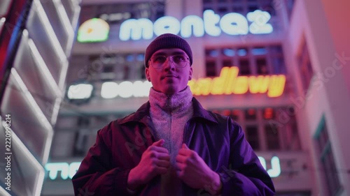 A young, fashionable man in the neon lights at night
