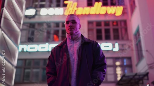 A young, fashionable man in the neon lights at night