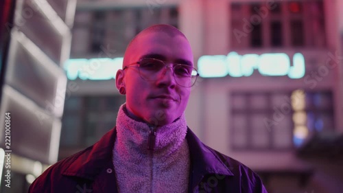 A young, fashionable man in the neon lights at night