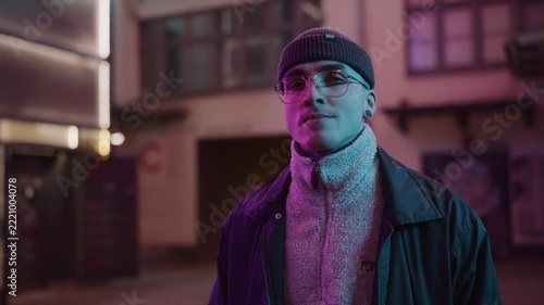 A young, fashionable man in the neon lights at night