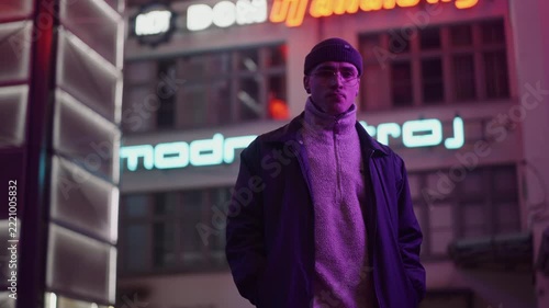 A young, fashionable man in the neon lights at night