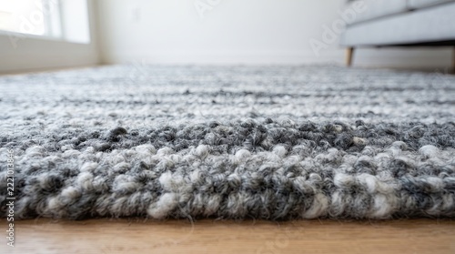 Woven wool carpet rests on a light hardwood floor beside sofa furniture.