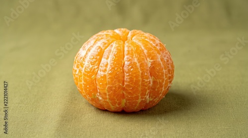 Tangerine sits peeled on a green textured fabric surface.