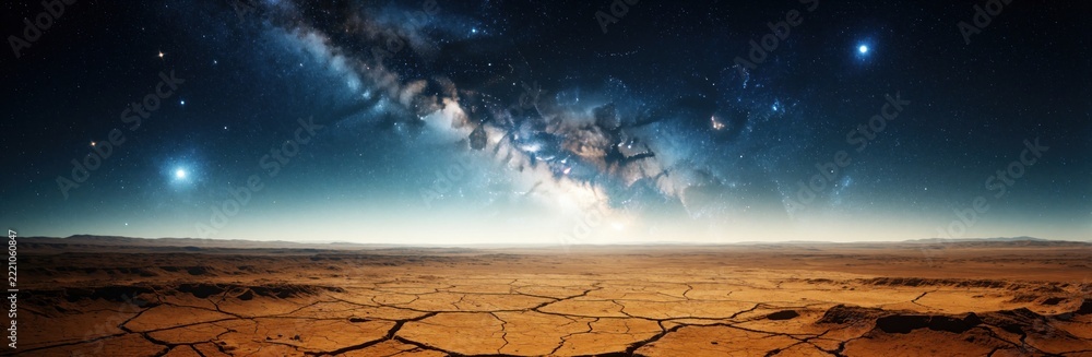 Fototapeta premium Wide panorama of milky way galaxy over dry cracked desert land. Bright stars, nebula glow in dark night sky above barren wasteland. Cosmic space background shows celestial light above empty sand