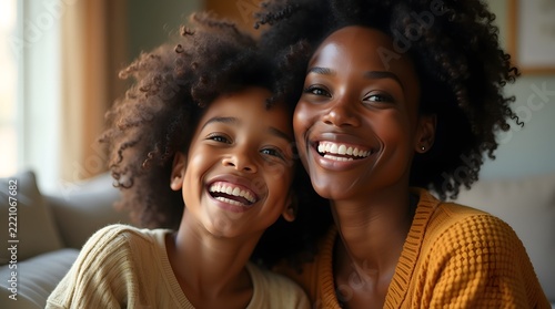 A joyful Black mother and her young daughter smile brightly, showcasing their beautiful curly hair and bright personalities.