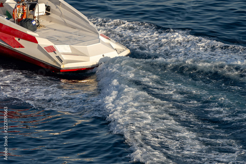 Red and white speed boat cruising fast on deep blue sea water