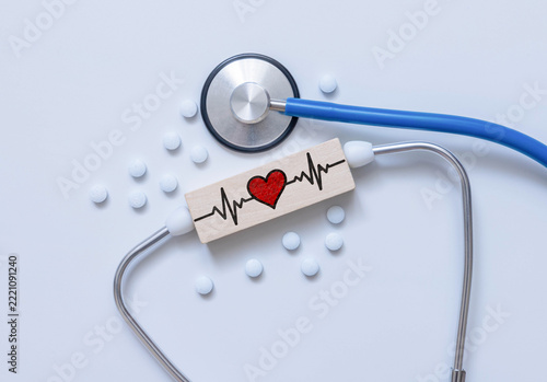 Heart Health and Cardiac Care Concept with ECG Heartbeat Symbol on Wooden Block, Stethoscope and Pills