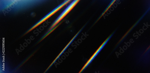 Abstract background with diagonal rainbow light leaks and lens flares on a dark textured surface