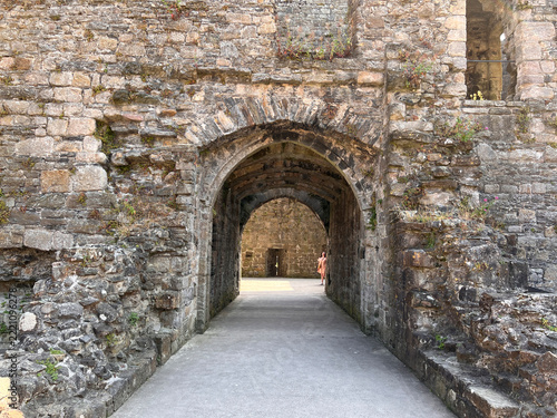 Beaumaris Castle, Isle of Anglesey, - july 17, 2026: A stone archway and passage lead through the weathered walls of a medieval castle ruin, with a distant figure standing in the sunlit courtyard beyo