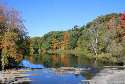 Trees in fall foliage reflecting on Yamaska River