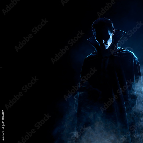 Mysterious Vampire Silhouette in Cape With Fog on Dark Background